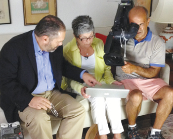 Beacon Hill Village member Joanne Cooper is filmed as she shares photos of her recently deceased partner to PBS NewsHour reporter Ray Suarez.